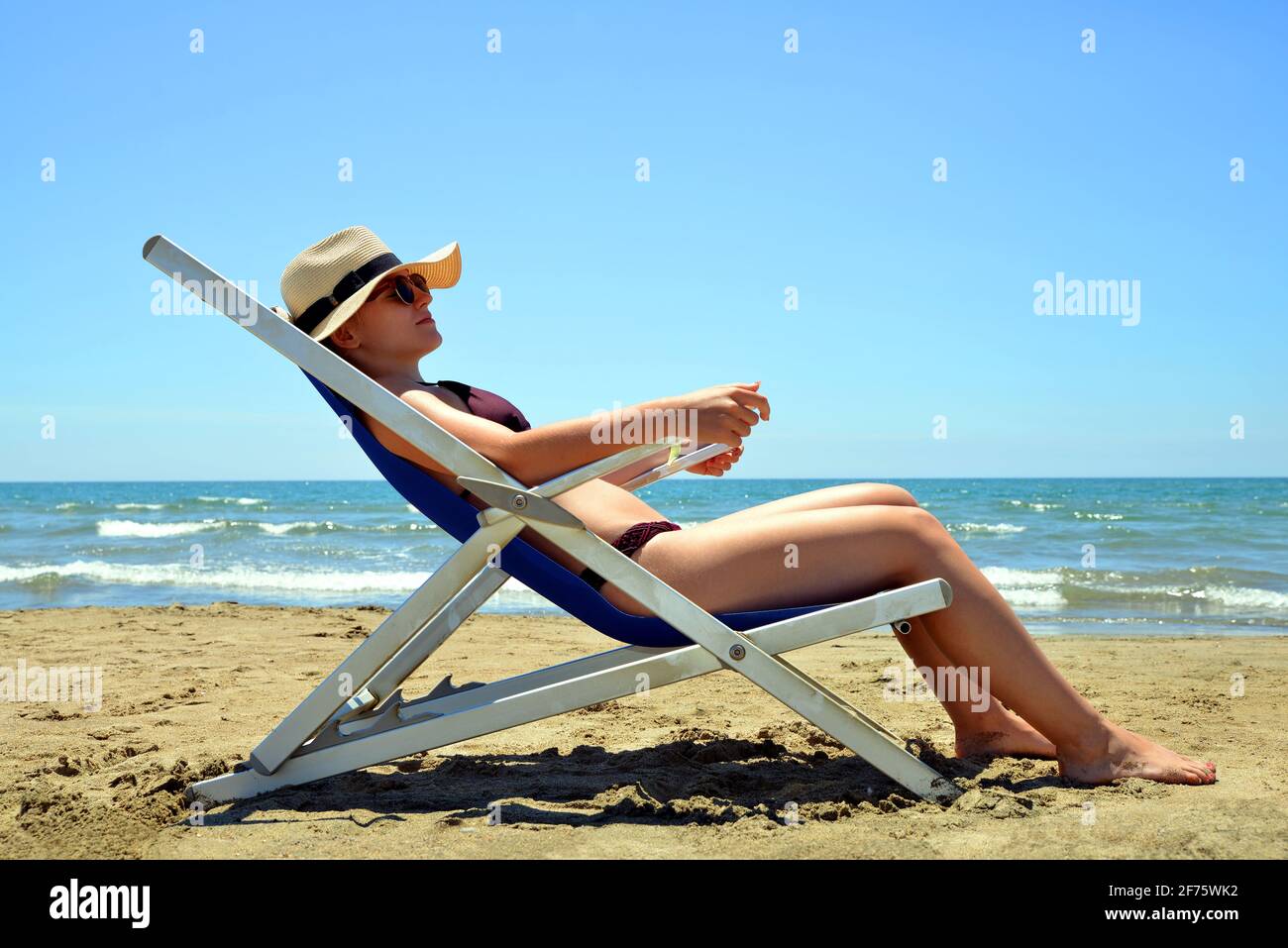 Une jeune fille allongé sur une chaise longue sur une plage de sable.  Vacances d'été au bord de la mer Photo Stock - Alamy