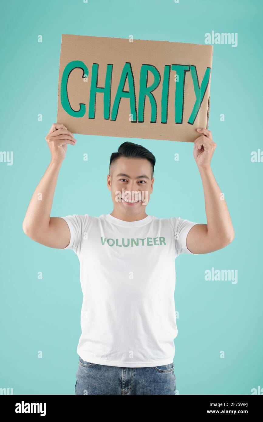 Portrait d'un jeune asiatique souriant et charmant tenant une pancarte inscription à une œuvre caritative et vue sur l'appareil photo Banque D'Images