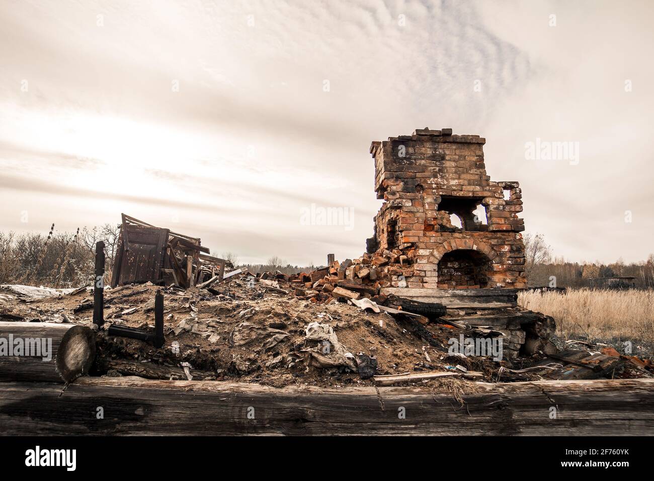 Un poêle de chauffage détruit debout seul dans un lot vacant. Maison brûlée au sol après l'incendie. En arrière-plan, il y a un ciel gris sombre. Une image tragique qui crée la solitude et la solitude. Banque D'Images