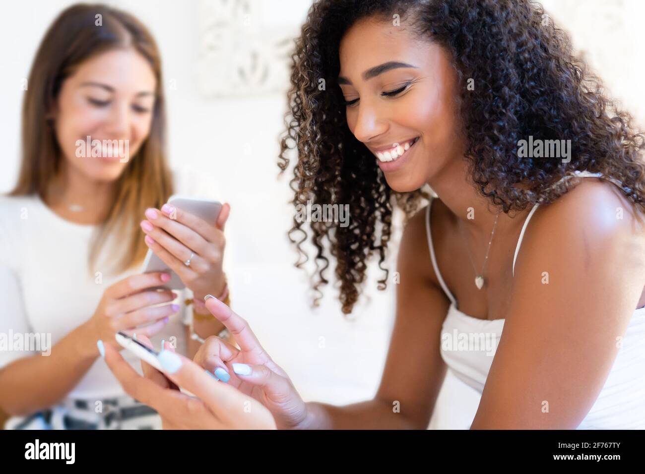 Deux heureux multiracial femmes amis s'amusant à la maison avec des achats en ligne. Concept de consumérisme dû à la nouvelle mobileconnection d'Internet et shopaholic h Banque D'Images