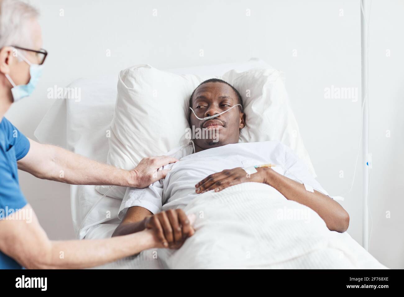 Portrait de l'homme afro-américain couché dans le lit d'hôpital avec un  médecin senior le réconfortant, espace de copie Photo Stock - Alamy