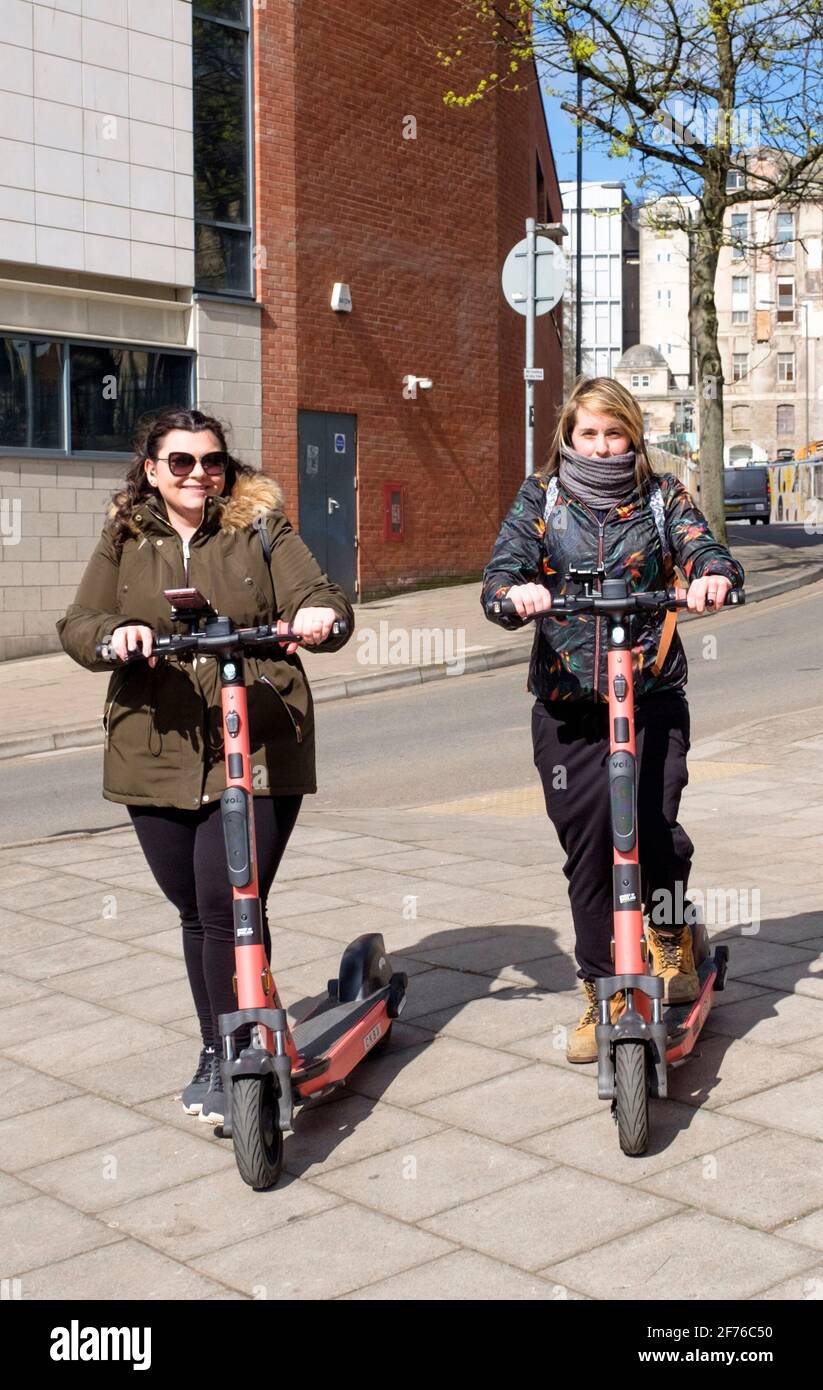 Deux jeunes femmes essaient des trottinettes VOI E dans le centre-ville de Bristol. Banque D'Images