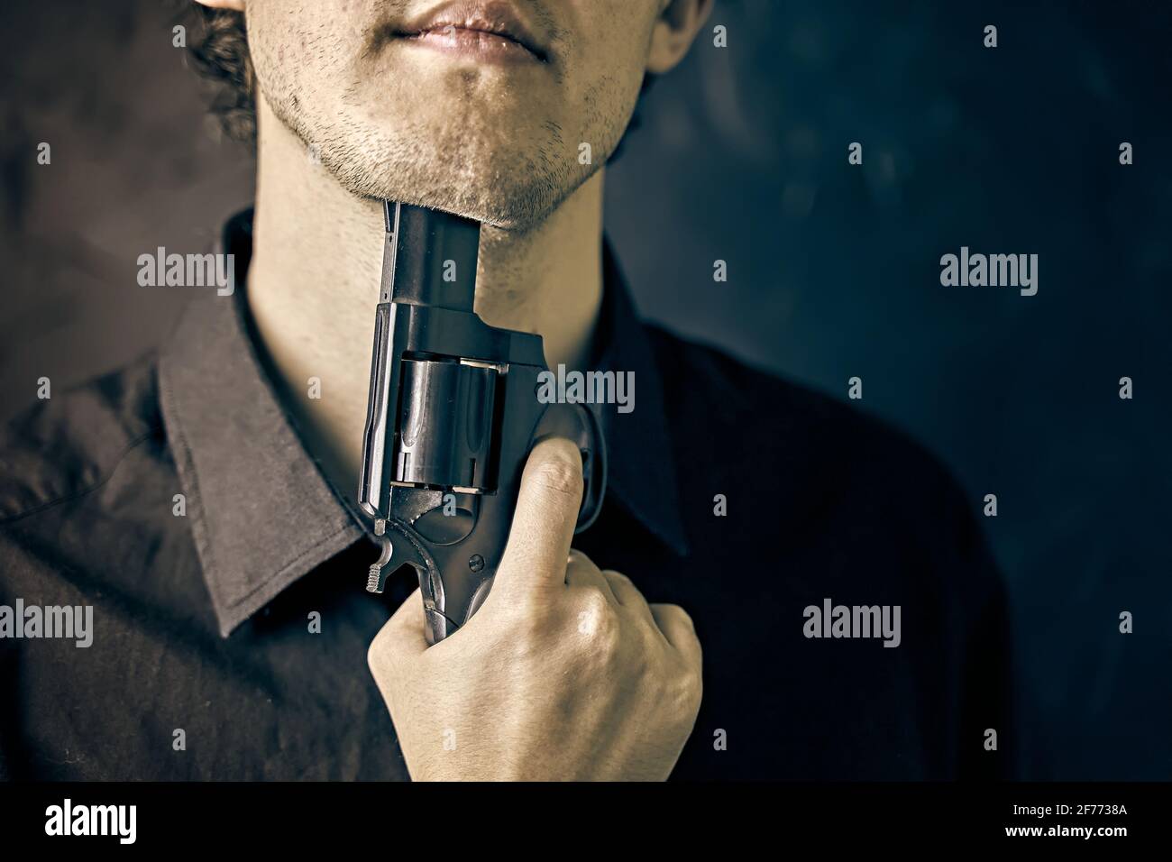 L'homme avec un fusil se prépare à commettre le suicide. Dépression avec issue fatale. Le jeune homme a mis un museau de fusil sur son menton. Banque D'Images