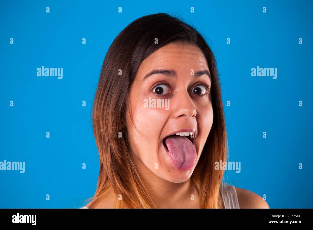 Femme avec la langue dehors avec un fond bleu Banque D'Images