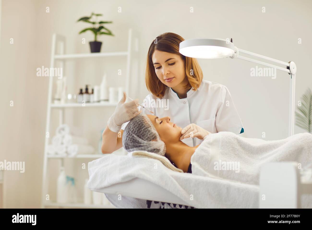 Femme obtenant une injection de beauté faciale avec une seringue de femme cosmetologiste Banque D'Images