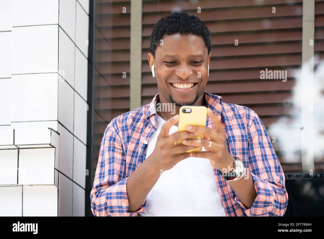 Homme afro-américain utilisant son téléphone dans la rue. Banque D'Images