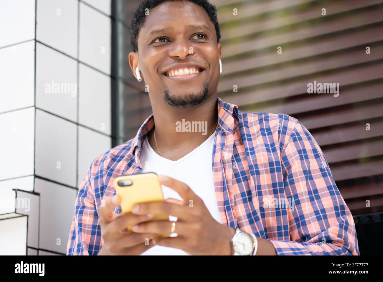 Homme afro-américain utilisant son téléphone dans la rue. Banque D'Images
