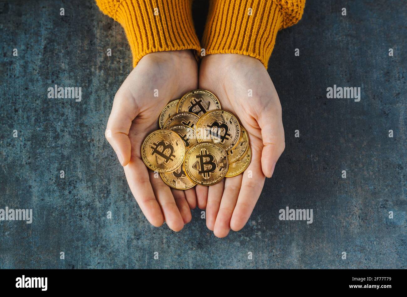 Vue de dessus de deux mains pleines de bitcoins sur un arrière-plan texturé. Golden coins BTC, marché boursier des crypto-monnaies concept et numérique décentral Banque D'Images