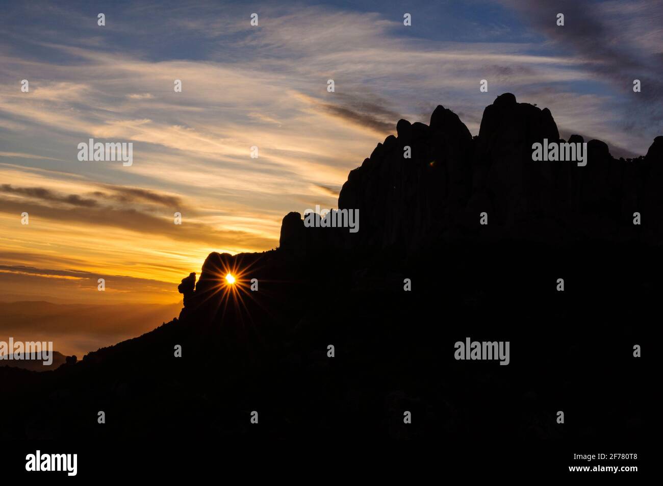 Roca Foradada de Montserrat avec le soleil levant à travers le trou de roche vu de Sant Pau Vell de la Guàrdia au lever du soleil avec le ciel rouge, Barcelone, Espagne Banque D'Images