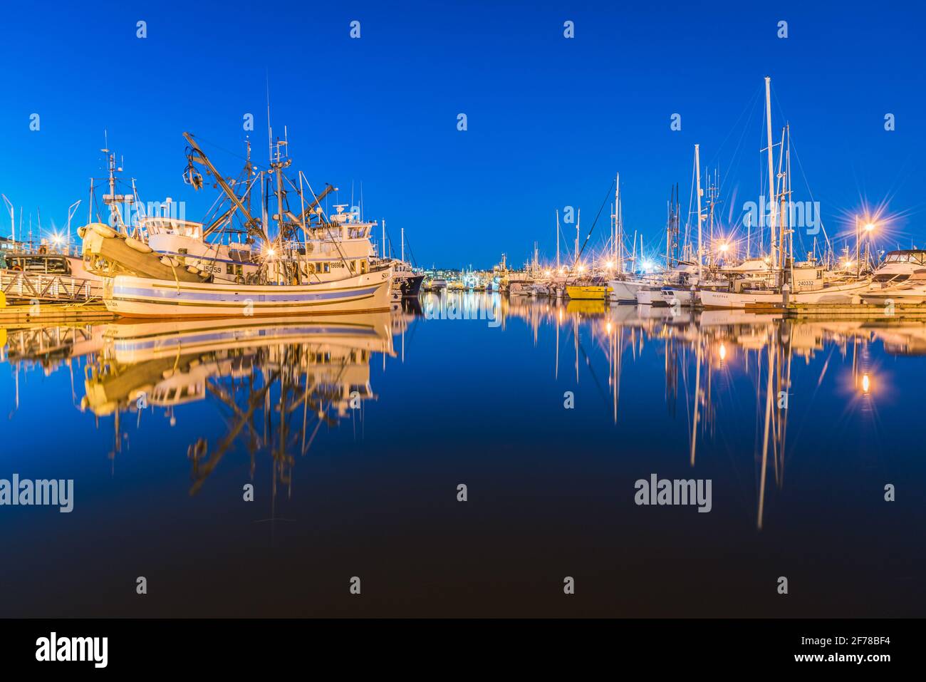 Les bateaux réfléchissent dans l'eau lors d'une nuit sans nuages au Fisherman's Terminal dans le quartier interbay de Seattle qui abrite Flotte de pêche du Pacifique Nord Banque D'Images