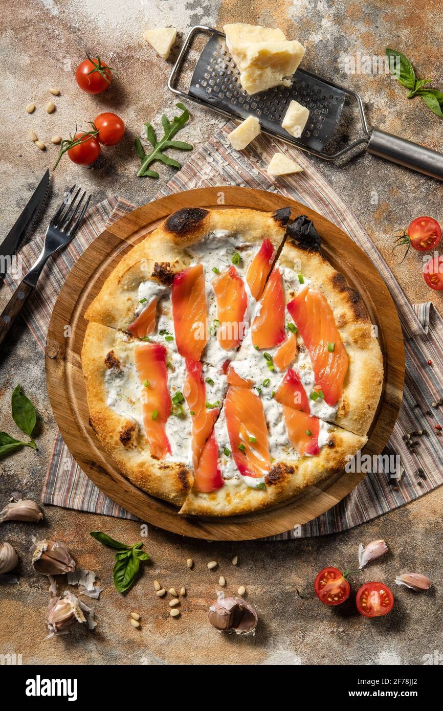 Pizza italienne avec saumon sur une planche de bois. Banque D'Images