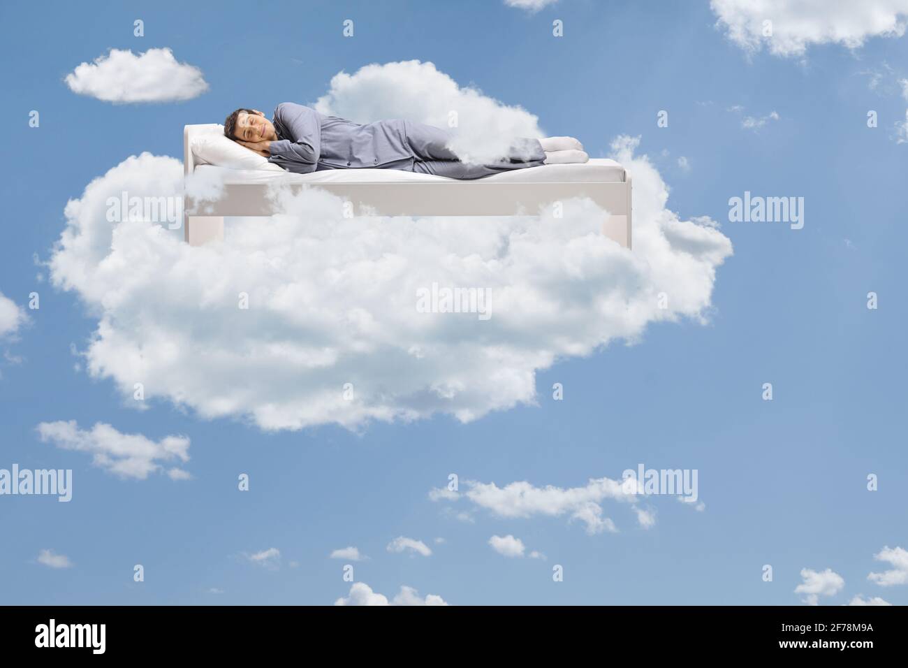 Homme dormant paisiblement dans les nuages flottant sur son lit Banque D'Images