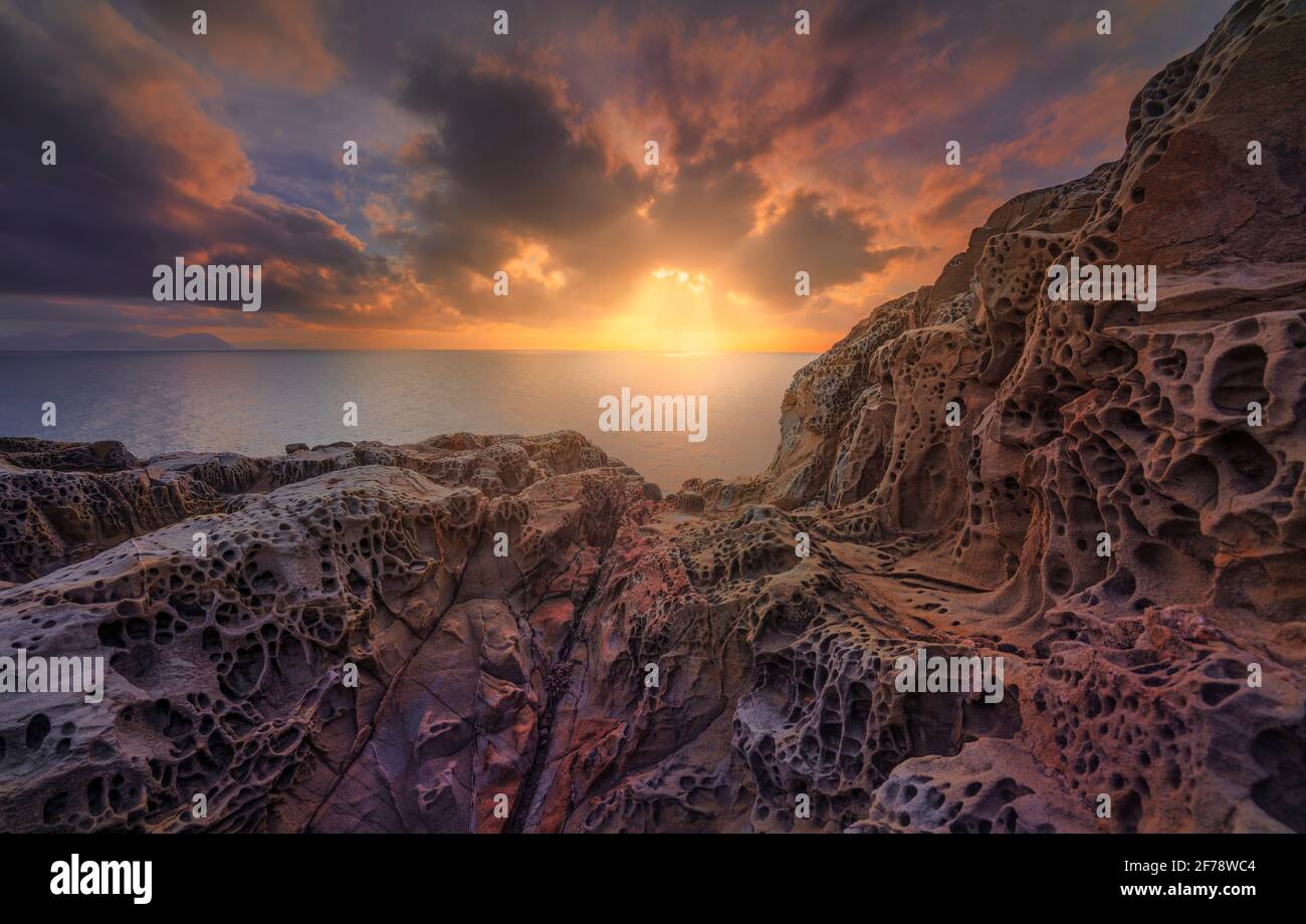 Mer au coucher du soleil et rochers érodés par le vent dans la falaise de Populonia Buca delle Fate. L'île d'Elbe à l'horizon. Paysage en Maremme. Piombino, Toscane, IT Banque D'Images
