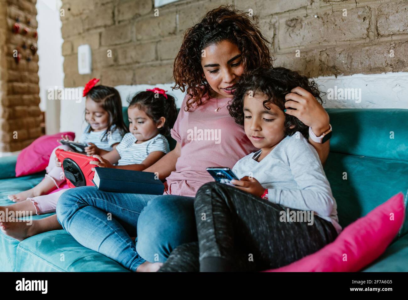 mère latine sur le canapé à la maison avec un petit garçon enfant Utilisez le téléphone pour naviguer sur Internet ensemble dans la ville de Mexico Banque D'Images