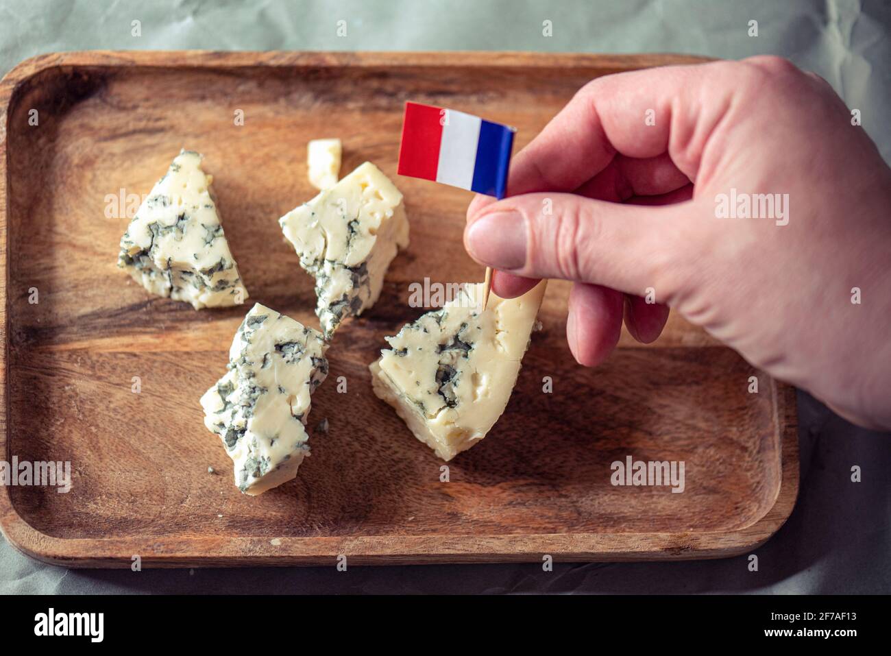 Un homme fermier mettant un petit drapeau français de papier sur le fromage bleu, la nourriture traditionnelle française Banque D'Images