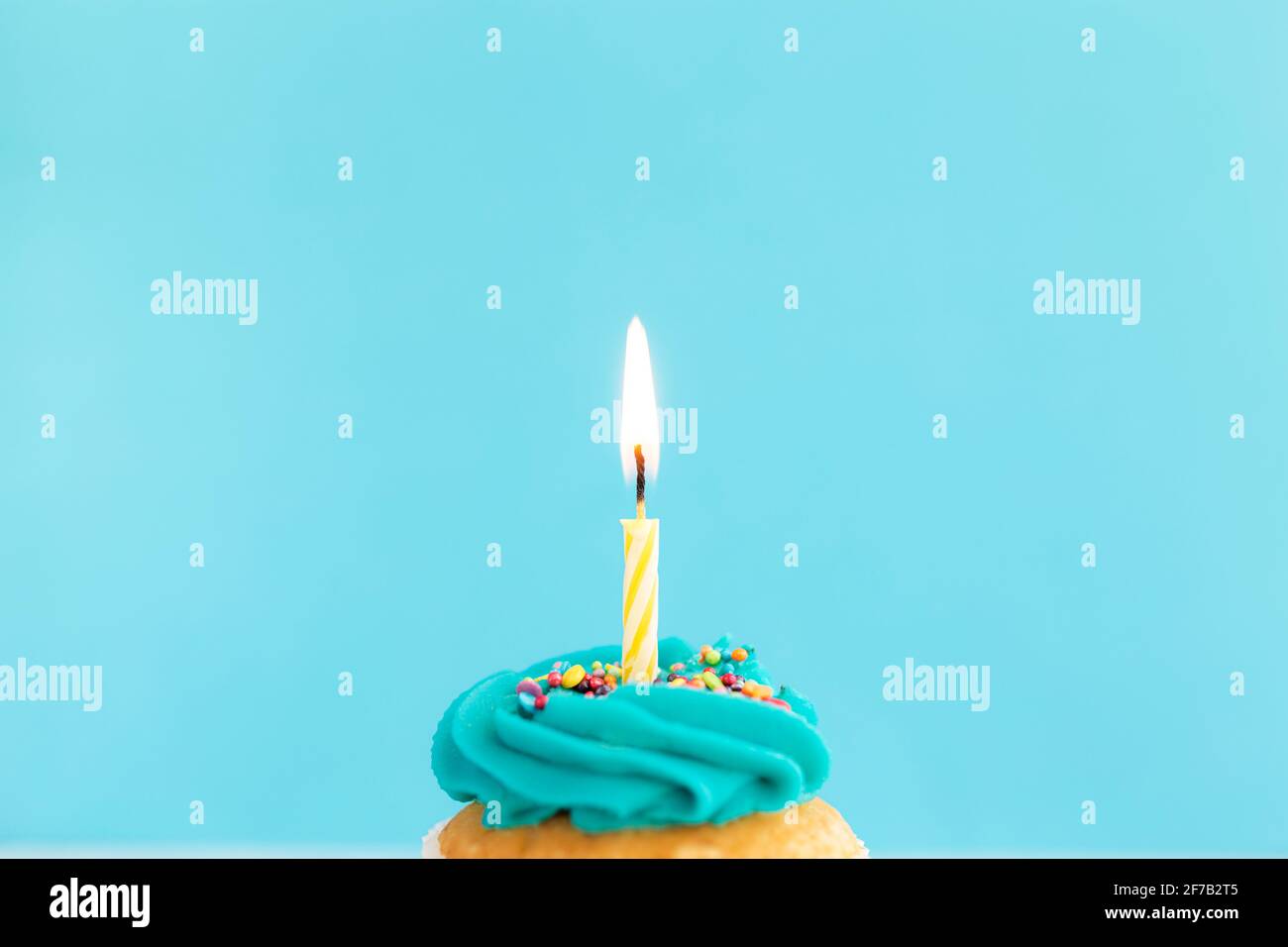 Concept de voeux d'anniversaire. Bougie allumée sur un muffin ou un cupcake. Arrière-plan bleu. Banque D'Images