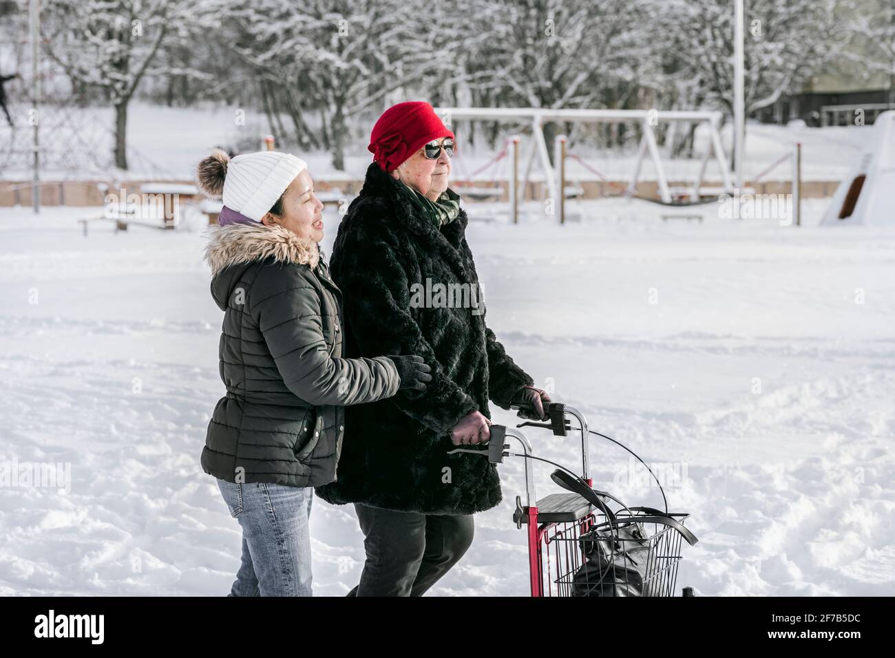 Femme âgée avec une femme aidant à domicile marchant l'hiver Banque D'Images