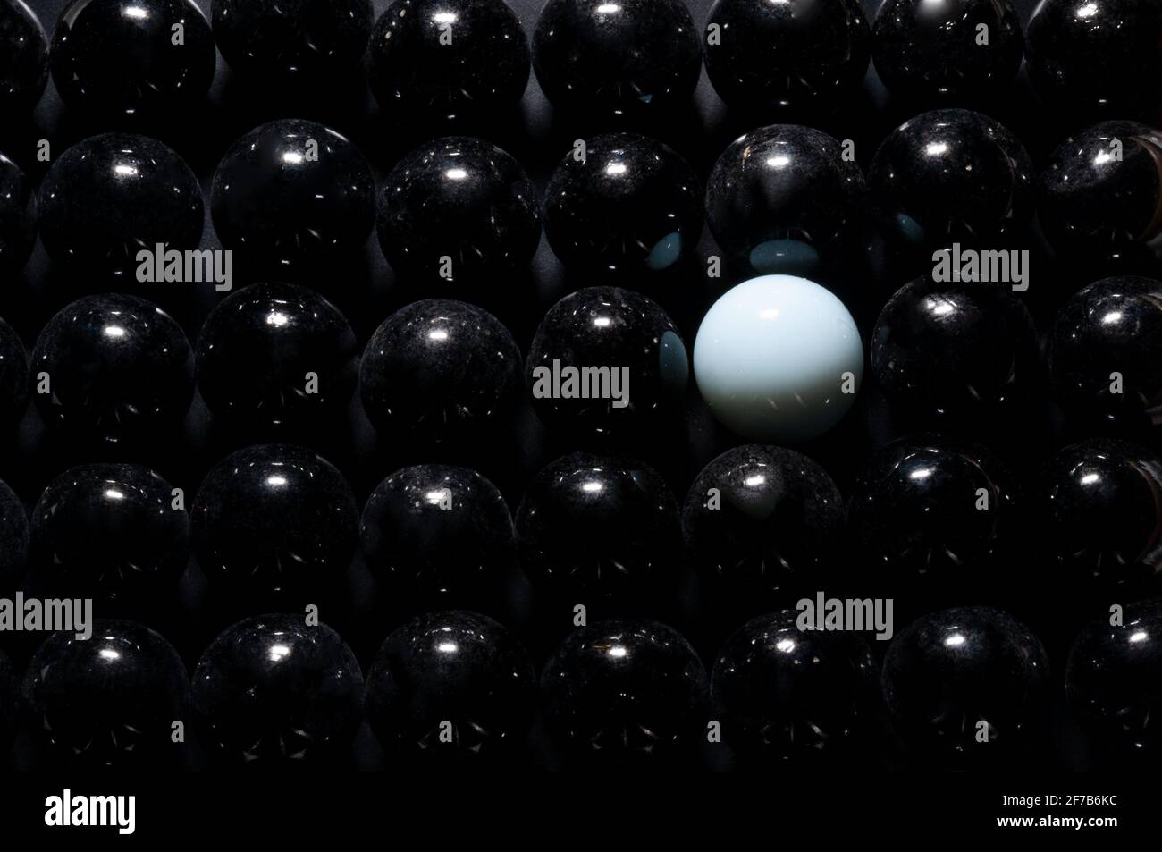 Sphère en verre blanc en arrière-plan de sphères noires vue rapprochée Banque D'Images