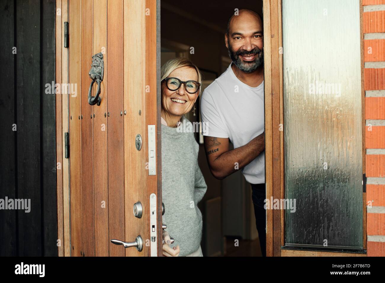 Couple mûr souriant à la porte d'entrée Banque D'Images