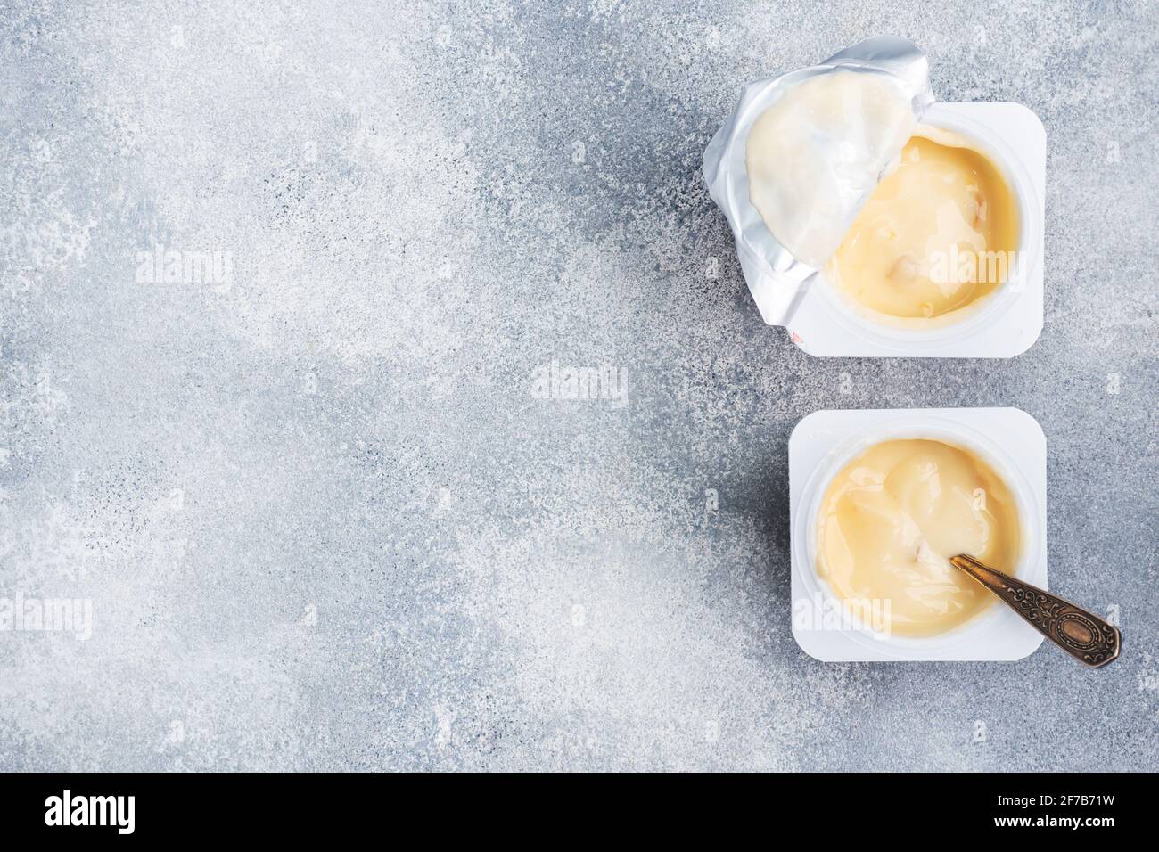 Yaourt de fruits au lait dans un paquet ouvert et une cuillère à café. Fond gris en béton, espace de copie Banque D'Images Yaourt de fruits au lait dans un paquet ouvert et une cuillère à café. Fond gris en béton, espace de copie Banque D'Images