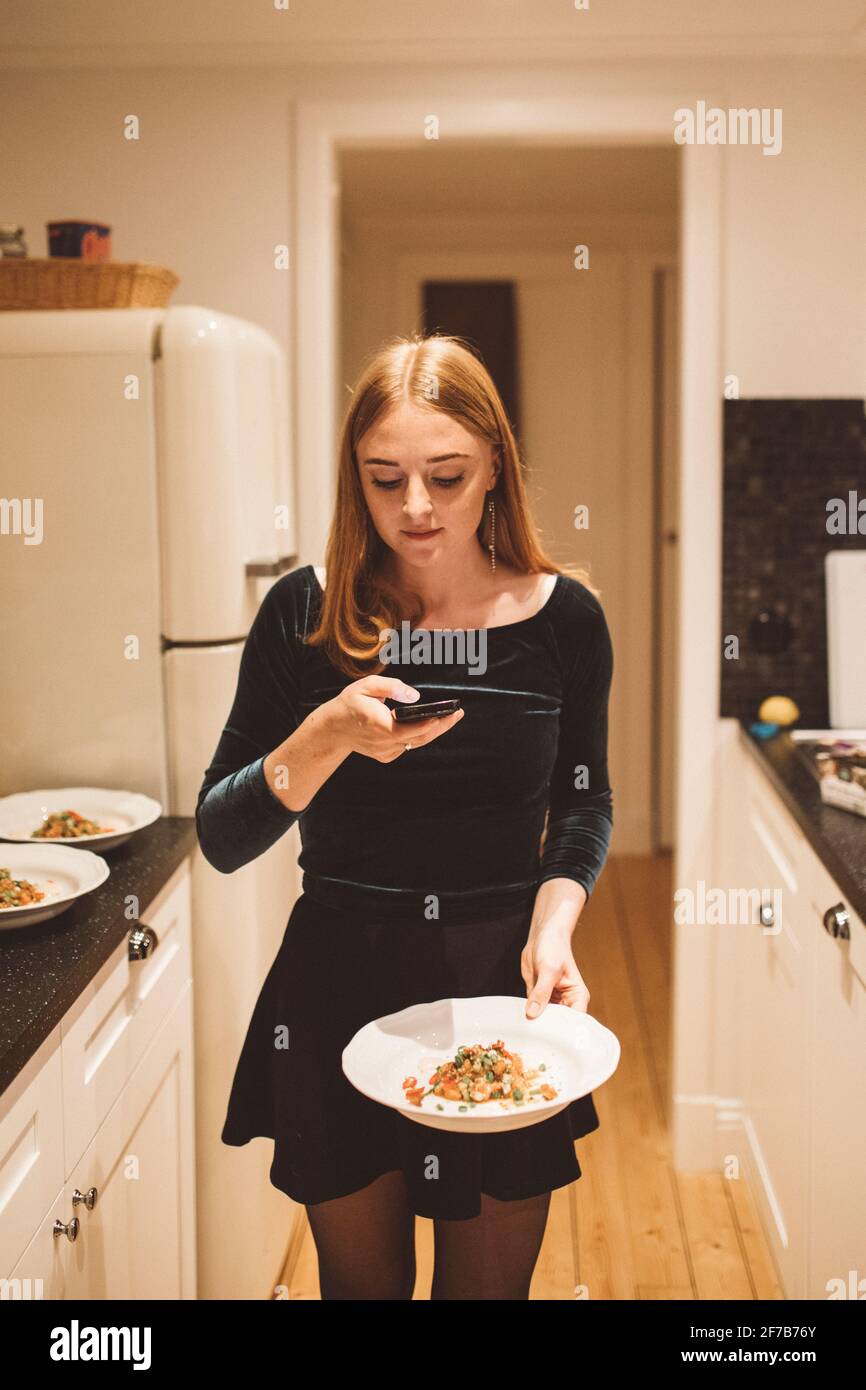 Femme en cuisine prenant la photo de la nourriture sur l'assiette Banque D'Images