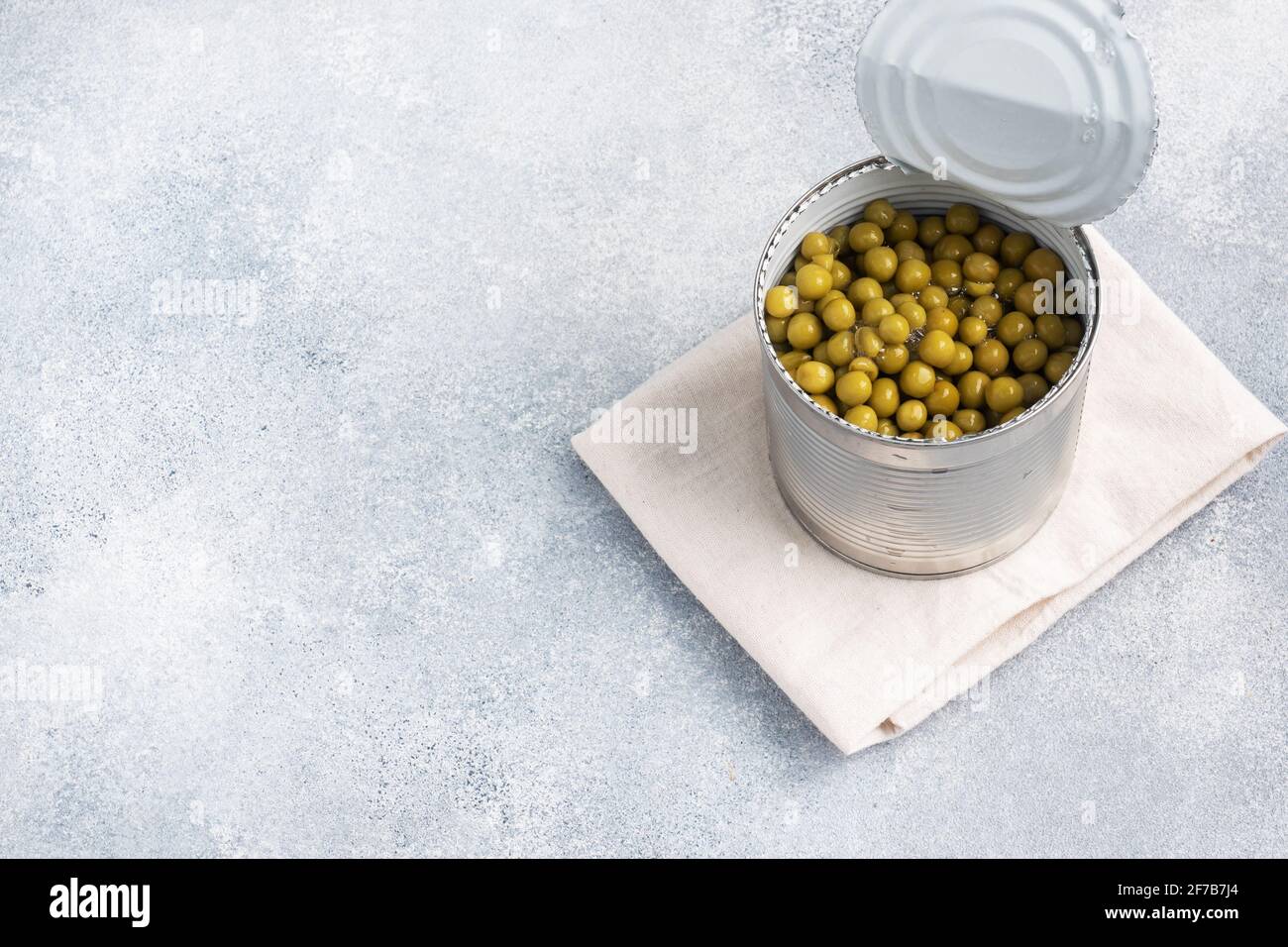 Boîte ouverte avec pois en conserve sur fond de béton gris. Espace de copie Banque D'Images Boîte ouverte avec pois en conserve sur fond de béton gris. Espace de copie Banque D'Images