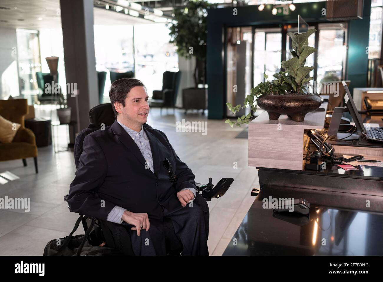 Homme d'affaires en fauteuil roulant dans le hall de l'hôtel Banque D'Images
