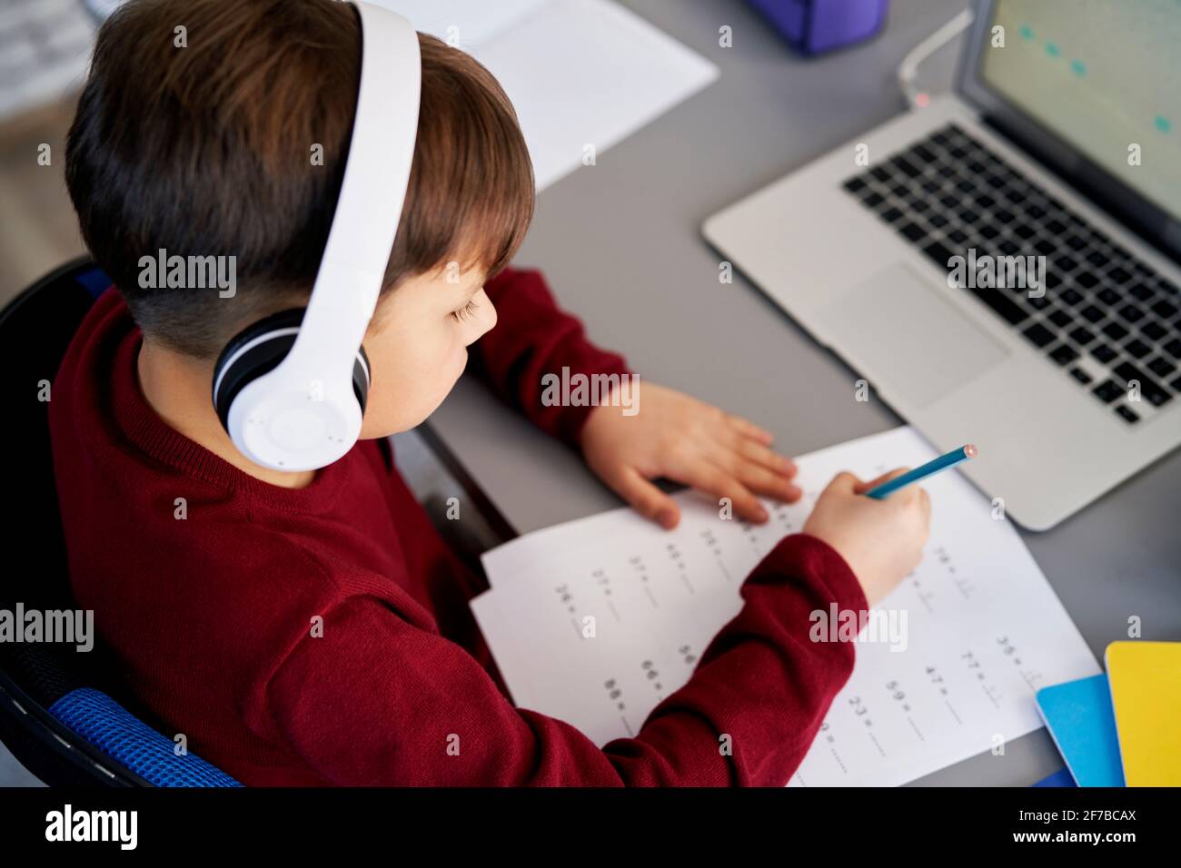 Vue de dessus d'un garçon qui fait ses devoirs pendant l'apprentissage en ligne Banque D'Images