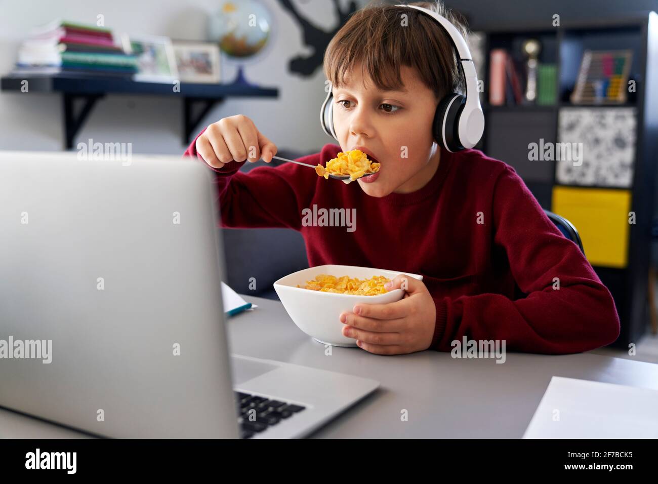 Garçon prenant le petit déjeuner pendant les cours en ligne Banque D'Images