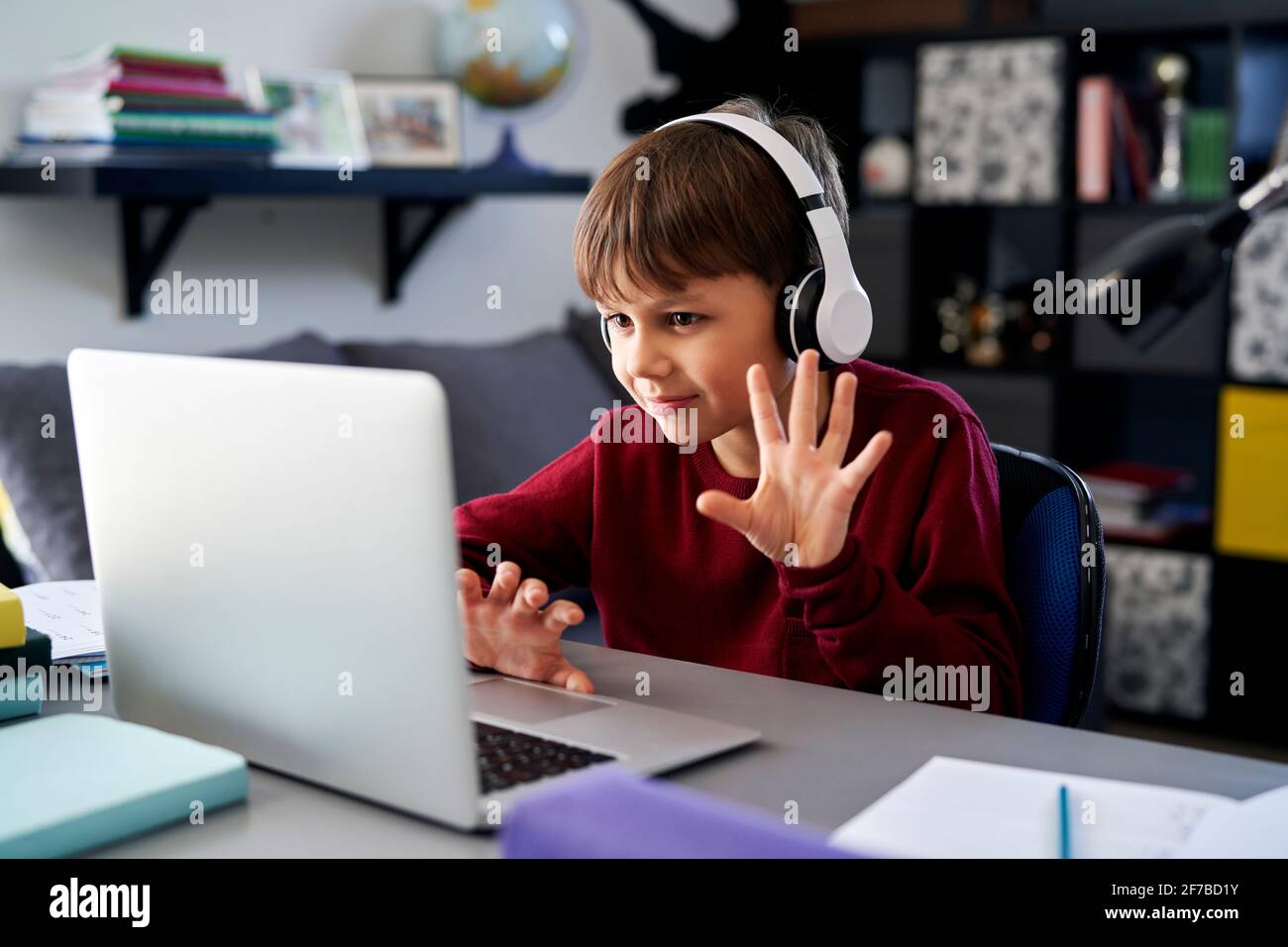 Garçon utilisant un ordinateur portable et agitant pendant un appel vidéo pendant les devoirs Banque D'Images