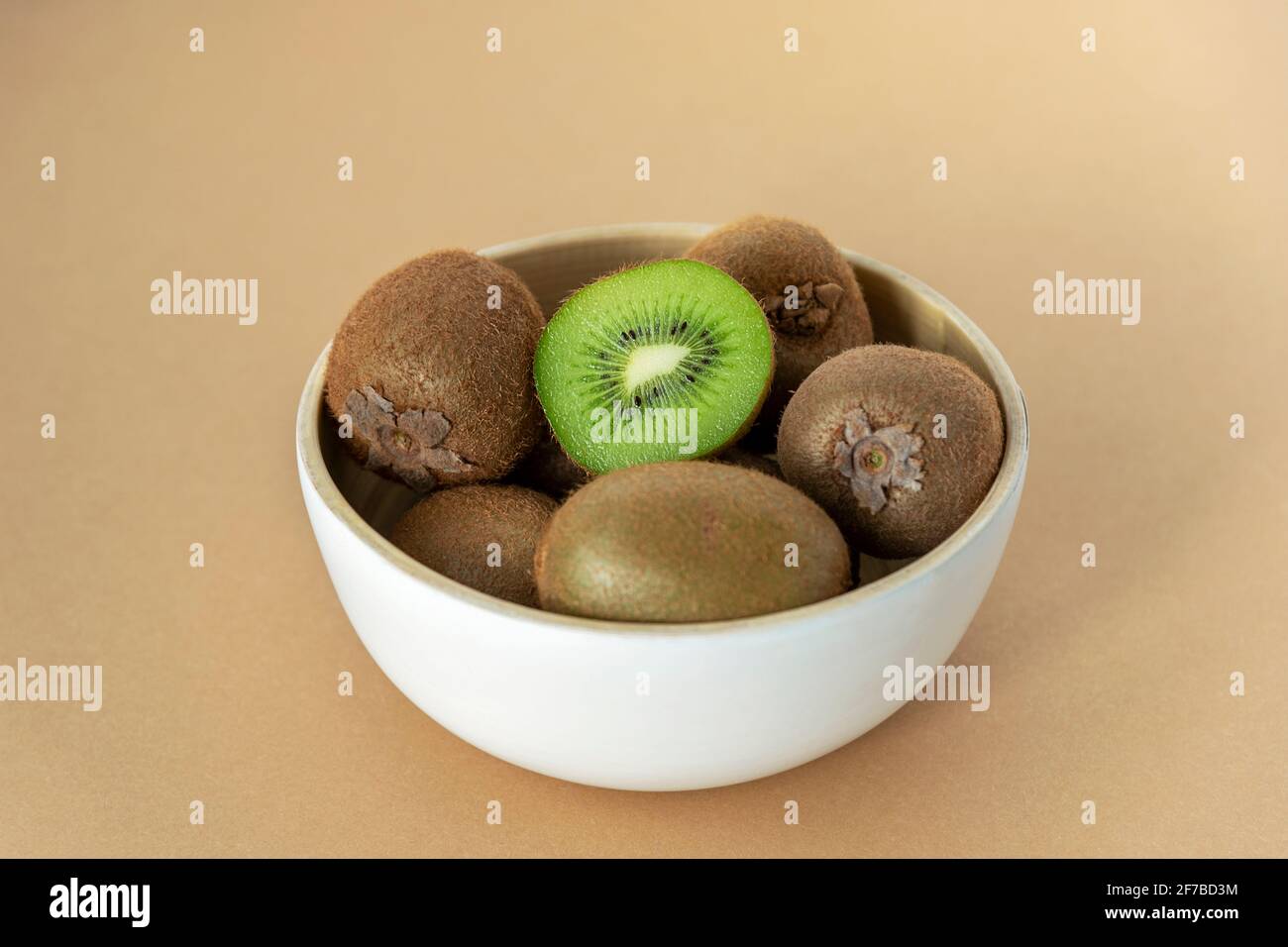 Kiwi dans un bol blanc sur fond beige. Concept d'alimentation saine. Gros plan. Banque D'Images