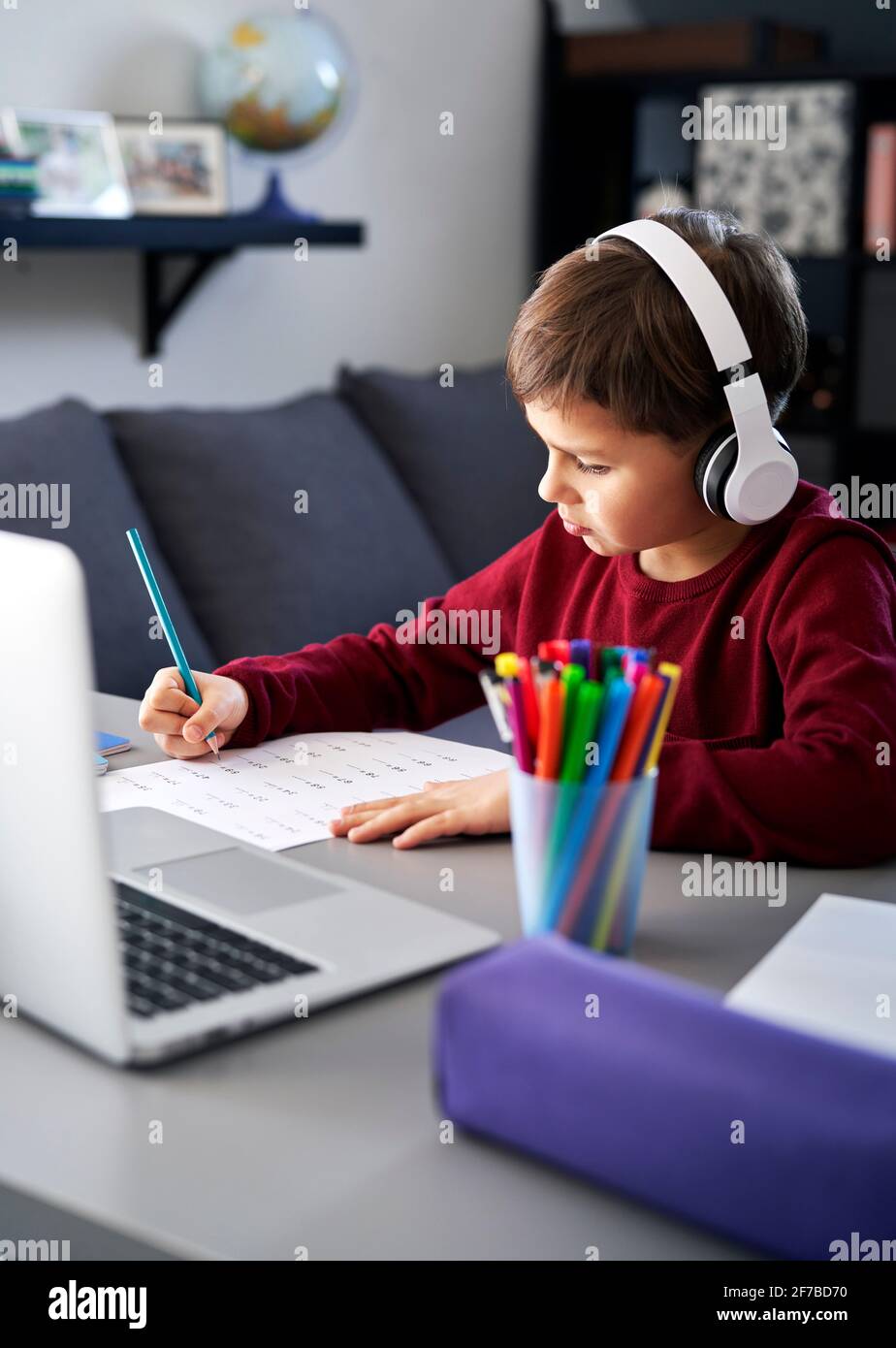 Un écolier diligent fait ses devoirs dans sa chambre Banque D'Images
