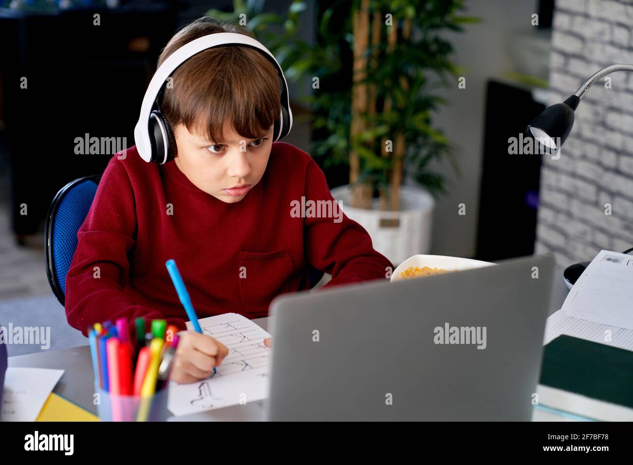 Écolier concentré pratiquant son écriture manuscrite Banque D'Images