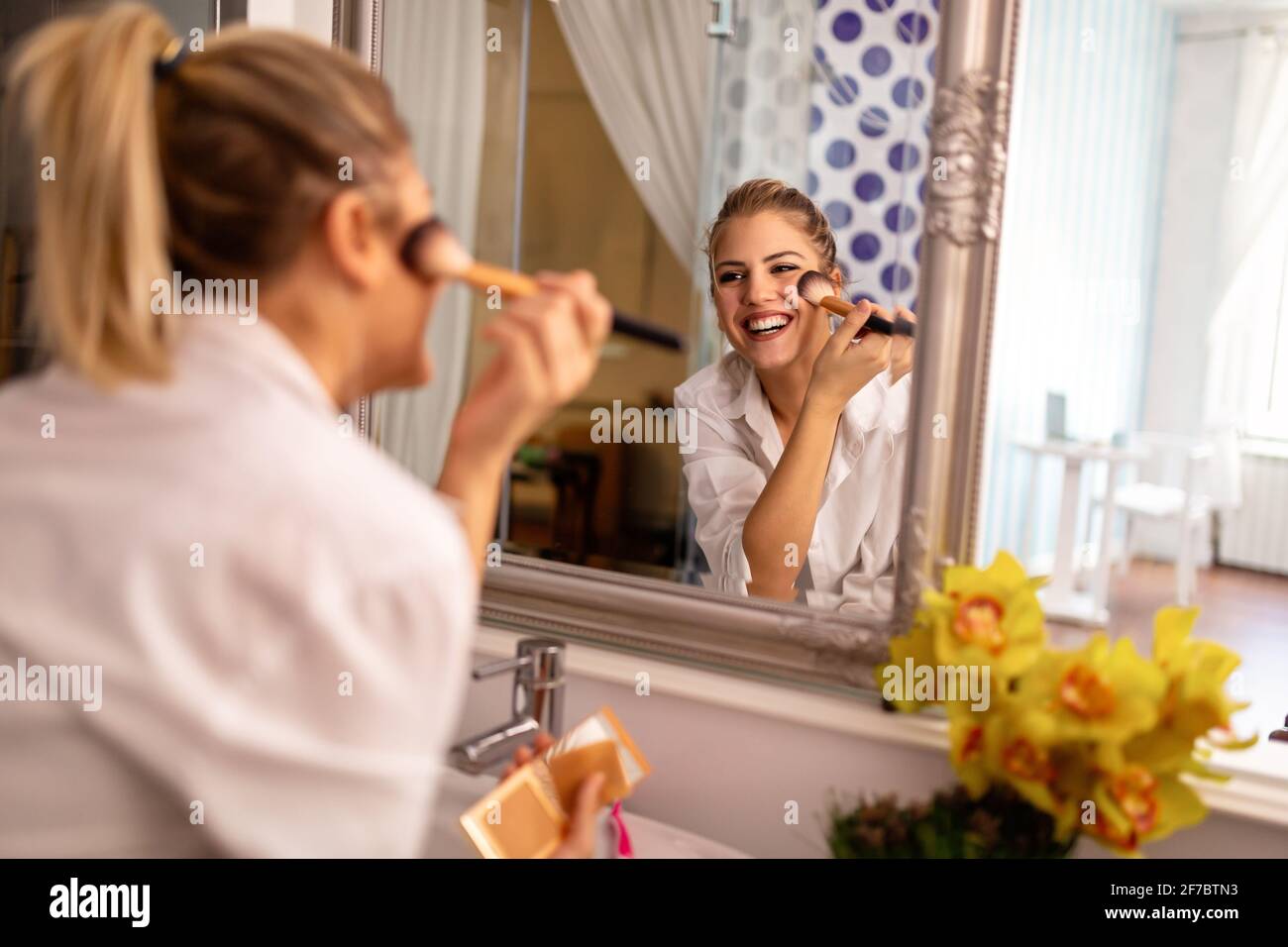 Belle femme faisant le maquillage devant le miroir à la maison Banque D'Images