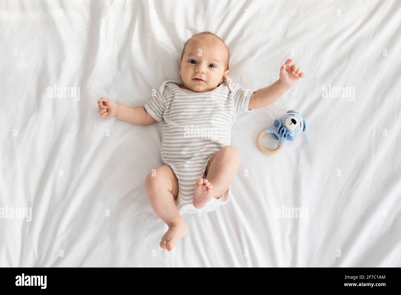 Adorable bébé nouveau-né portant un body allongé sur le lit et regardant à l'appareil photo Banque D'Images