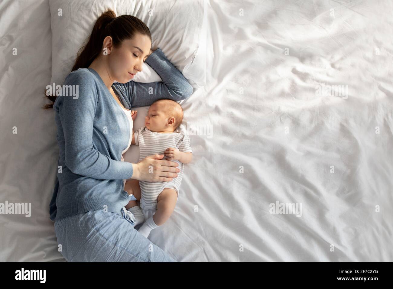Co-dormant avec bébé. Une jeune femme se couche au lit avec son nouveau-né Banque D'Images