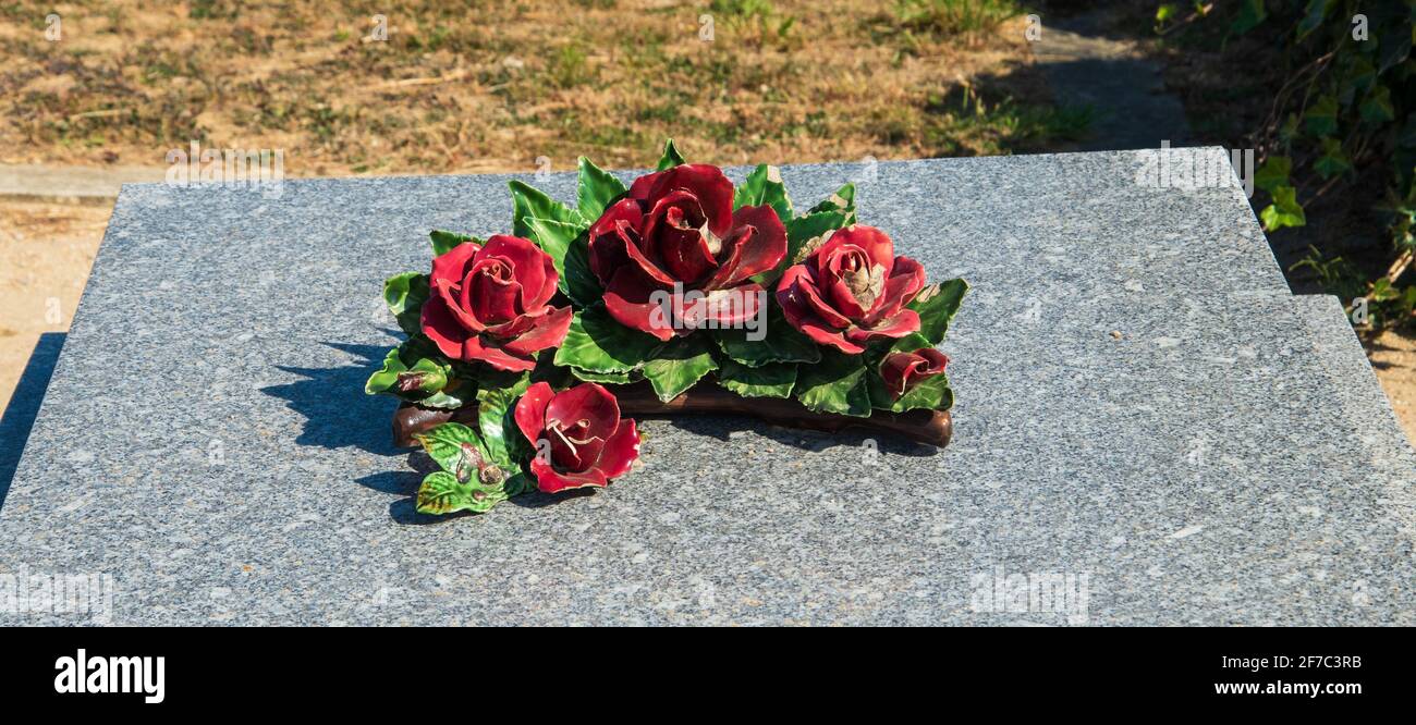 Fleurs roses en céramique rouge sur la tombe du cimetière. France.  Décoration traditionnelle en céramique. Mise au point sélective et faible  profondeur de champ. Deuil en arrière Photo Stock - Alamy