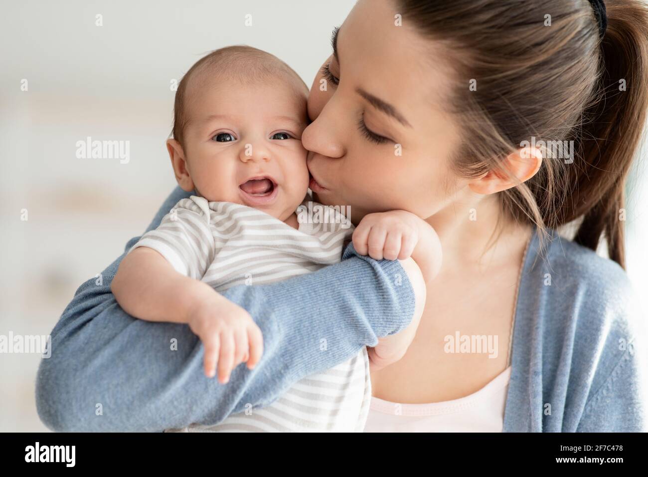 Amour de la mère. Gros plan Portrait de jeune maman qui embrasse son enfant nouveau-né mignon Banque D'Images