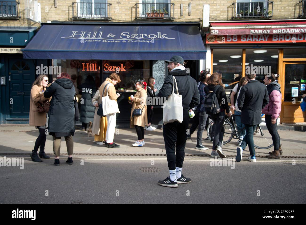 Londres, Angleterre, Royaume-Uni. Hackney. Champs de Londres. Marché de Broadway. Jeunes dans la rue devant les bouchers Hill et Szrok. Banque D'Images