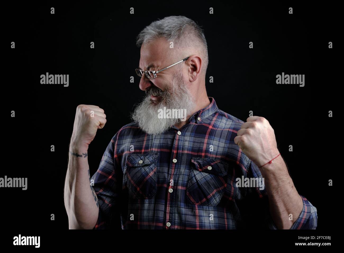 Portrait d'un homme européen mûr, joyeux et émotif, qui élève les poings et hurle, triomphant ou applaudisse tout en regardant un match de football Banque D'Images