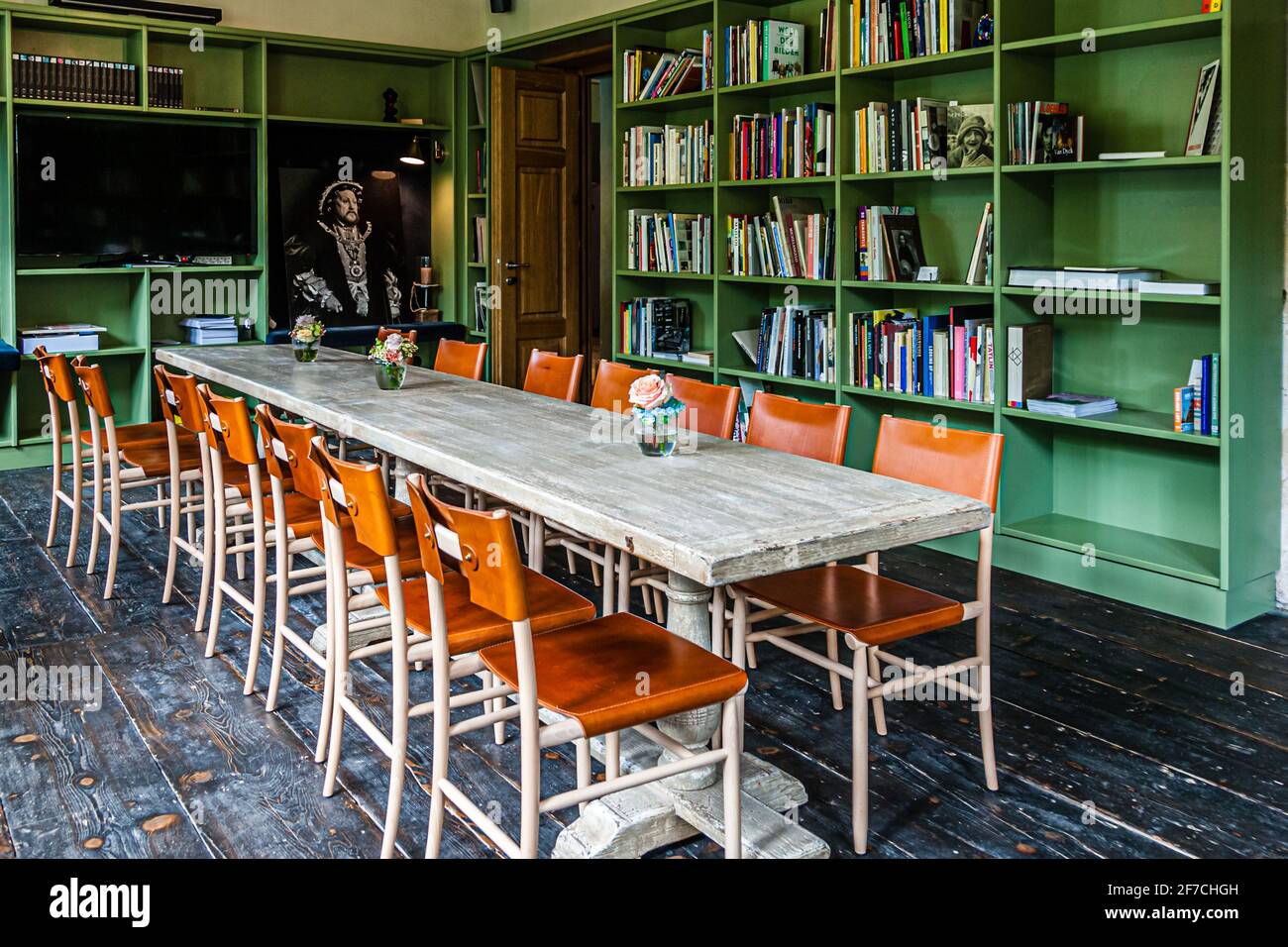 La bibliothèque de l'hôtel Renthof à Kassel, en Allemagne, remplie de lectures sur les artistes de la documenta, offre un espace pour un travail créatif à jusqu'à 20 invités de conférence. Des étagères peintes en vert remplies de livres et de catalogues encadrent une longue table en bois avec des chaises en cuir ; par la suite, des plats du restaurant Renthof peuvent également être servis ici. Banque D'Images