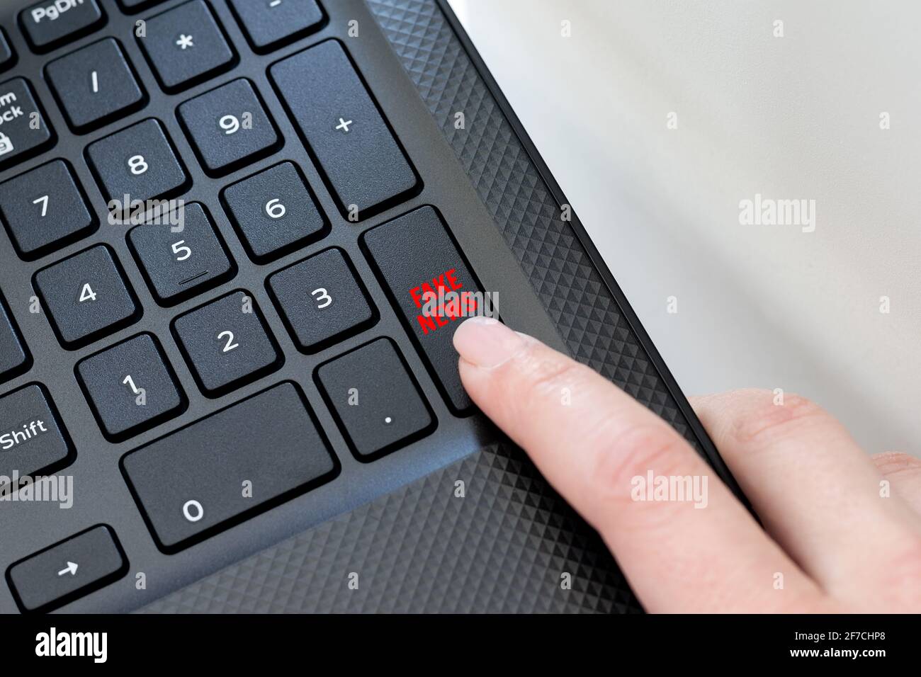 Coin clavier d'un ordinateur portable noir avec un doigt de femme en cliquant sur un bouton de fausses nouvelles. Le concept de la diffusion de fausses nouvelles, des messages sur Internet Banque D'Images