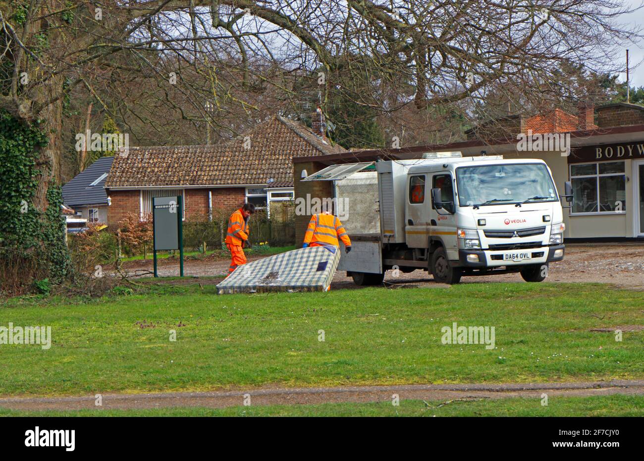 Un matelas à bout de mouche est collecté par les employés de l'entretien des autoroutes d'un petit vert dans le Borough de Hellesdon, Norfolk, Angleterre, Royaume-Uni. Banque D'Images