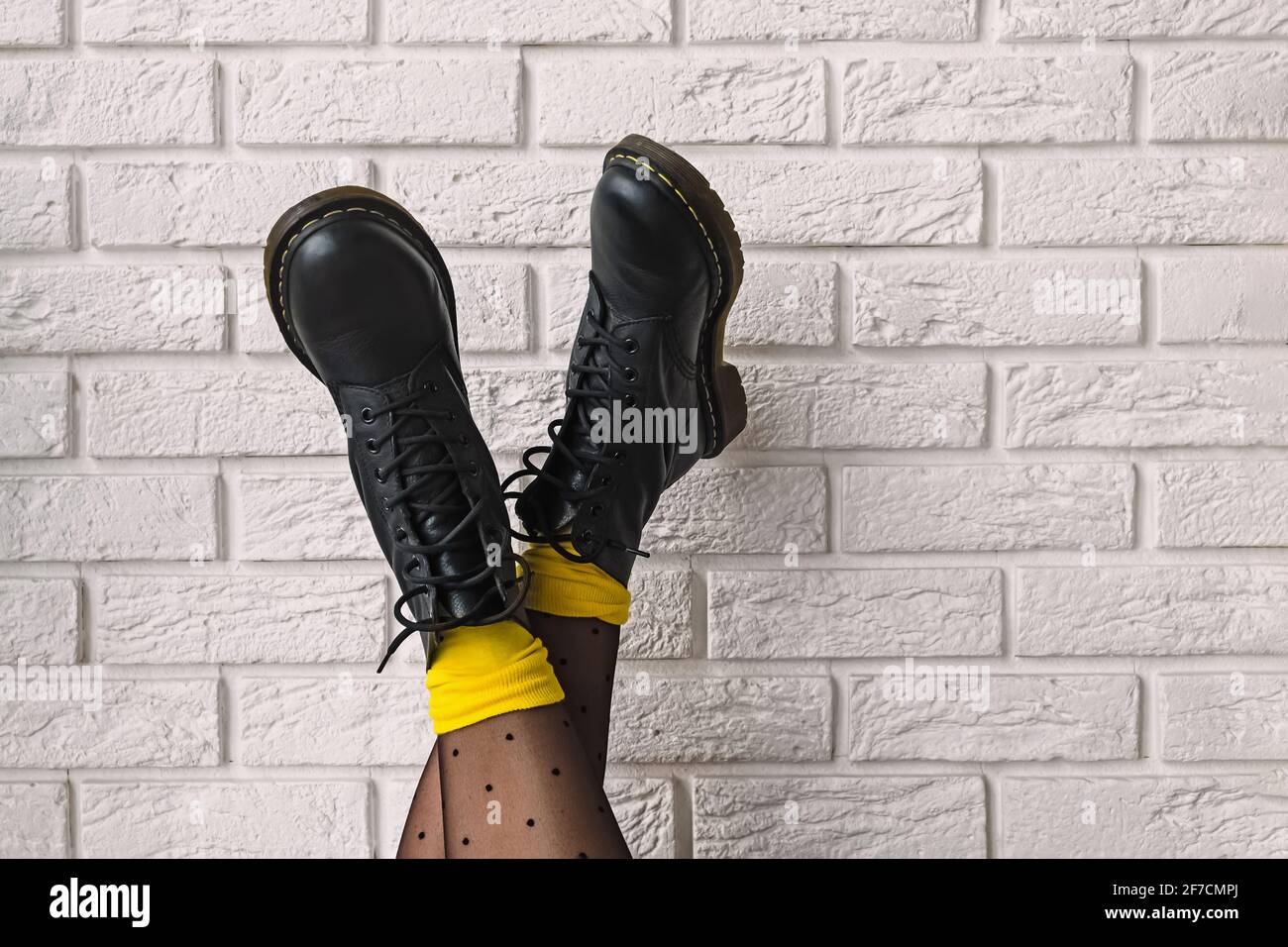 Pieds de femme en cuir noir avec collants à pois et des chaussettes jaunes Banque D'Images