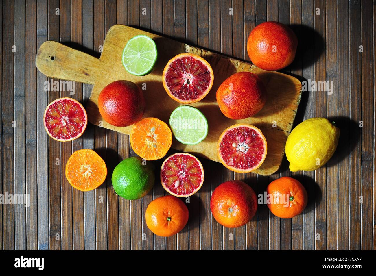 Oranges siciliennes rouges, chaux, citron et mandarine sur fond de bois de planche à découper Banque D'Images