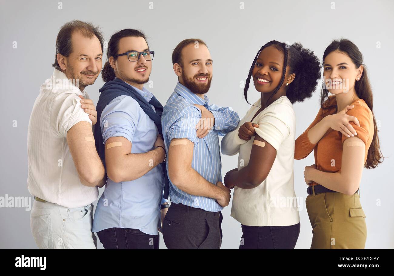 Portrait de groupe de studio de personnes joyeuses et variées montrant les bras après recevoir le vaccin Banque D'Images