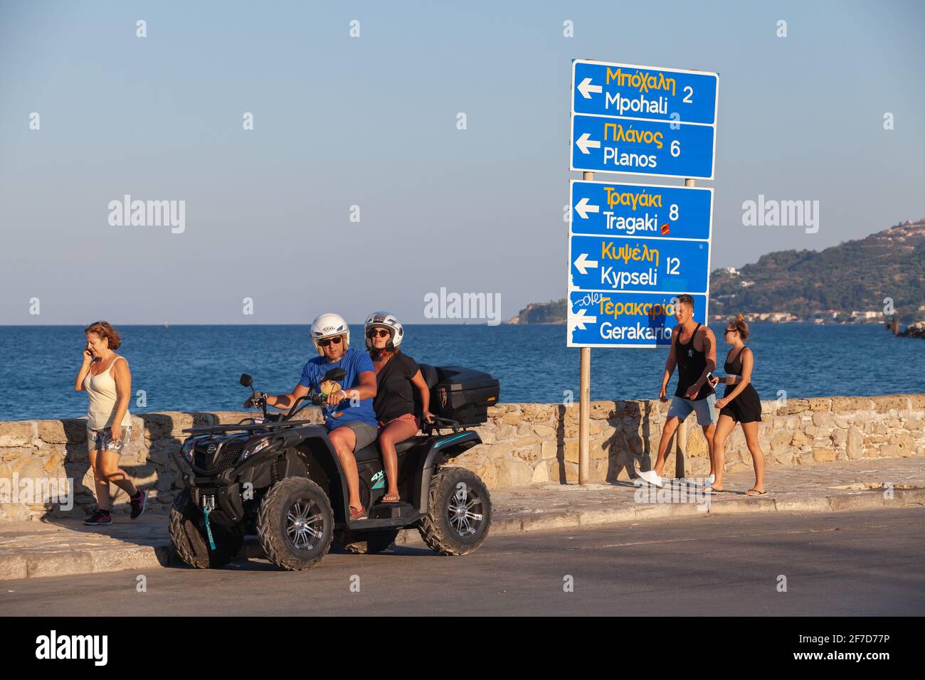 Zakynthos, Grèce - 14 août 2016 : les touristes font du quad dans une rue côtière de Zakynthos. Les gens ordinaires marchent à proximité Banque D'Images