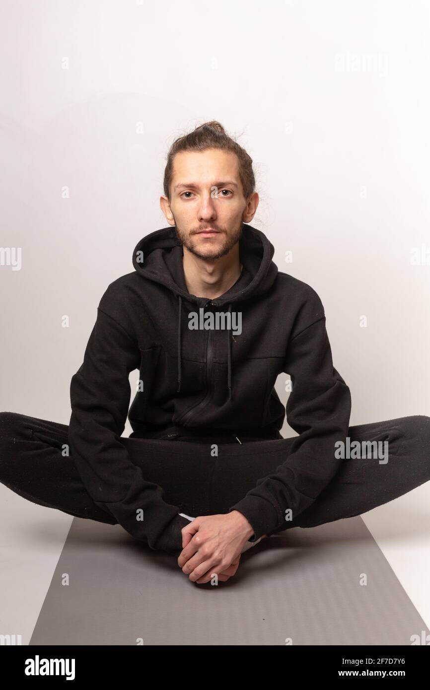 Un jeune homme assis à pieds croisés sur un tapis de yoga prêt à faire de l'exercice quotidien. Exercice, vie saine, maintien en forme concept Banque D'Images