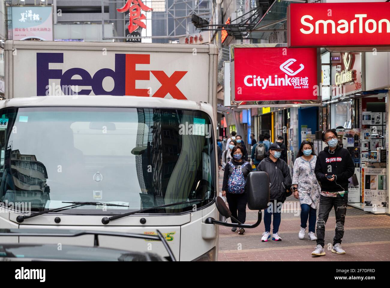 Promenez-vous à pied devant un camion de livraison American FedEx Express, des sociétés de télécommunications Citylink et SmarTone à Hong Kong. Banque D'Images
