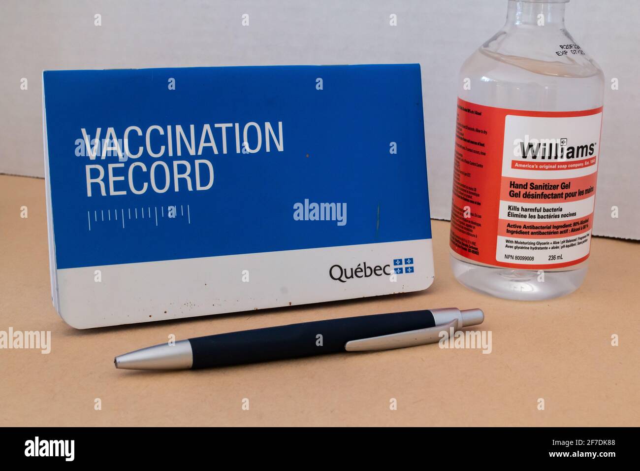 Toronto, Ontario, Canada - 2 février 2021 : un livret de vaccination du Québec à côté d'une bouteille de désinfectant pour les mains et d'un stylo. Banque D'Images